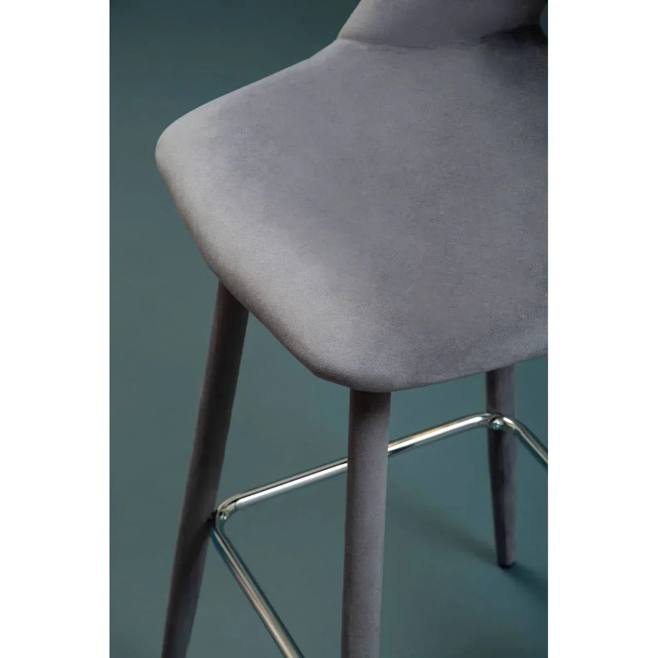 Grey upholstered bar stool with chrome footrest and angled wooden legs