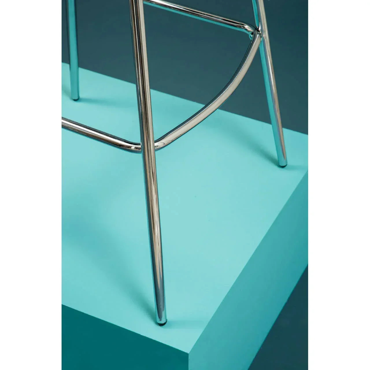Chrome chair legs with footrest on blue platform, close-up angle