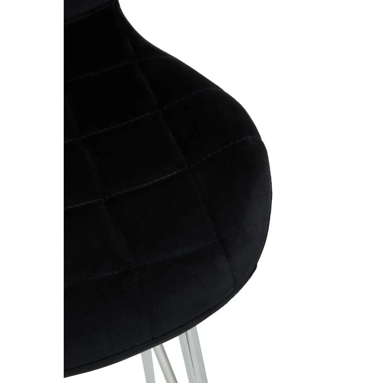 Black velvet dining chair seat with quilted stitching and chrome legs, close-up view
