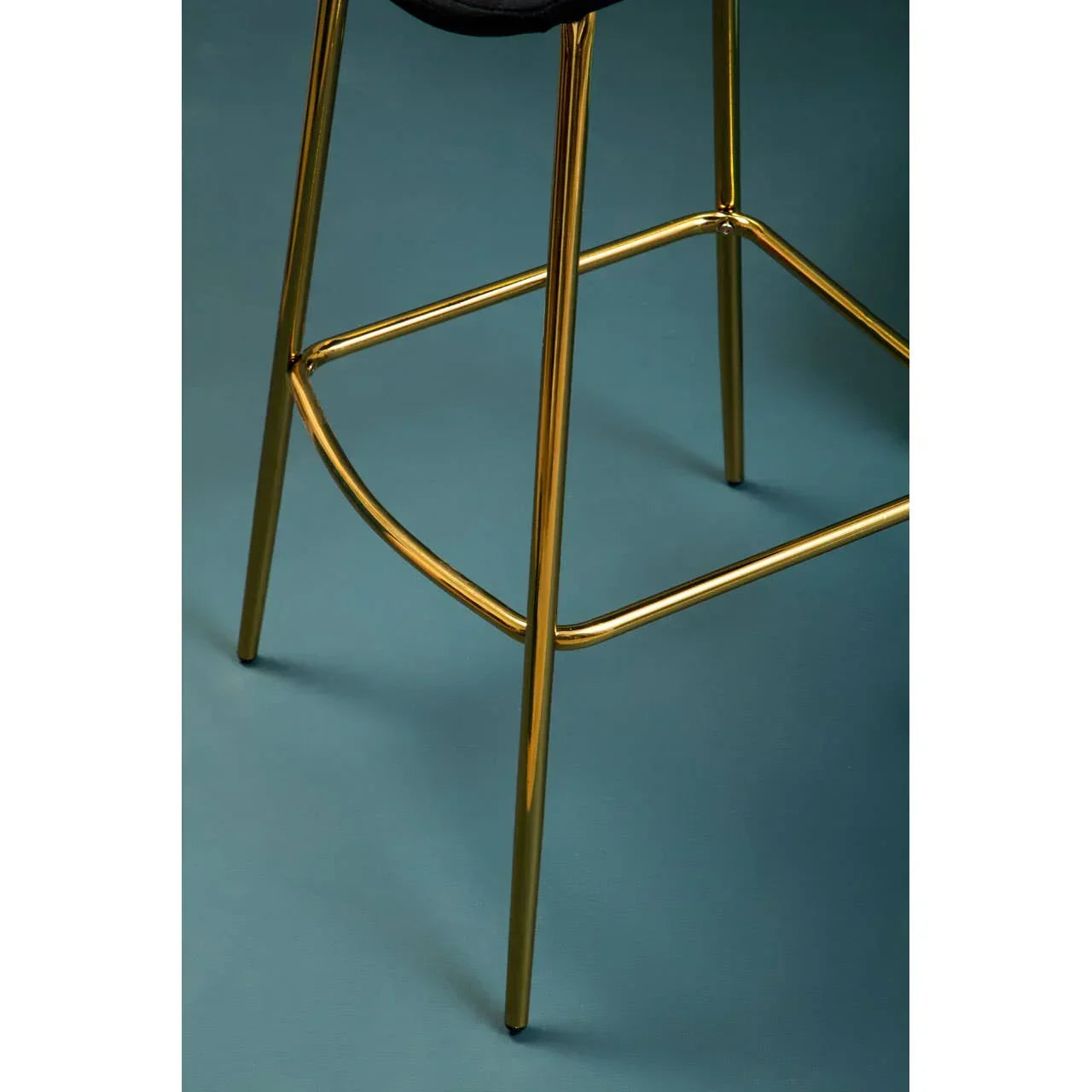 Gold metal bar stool legs with footrest on blue floor