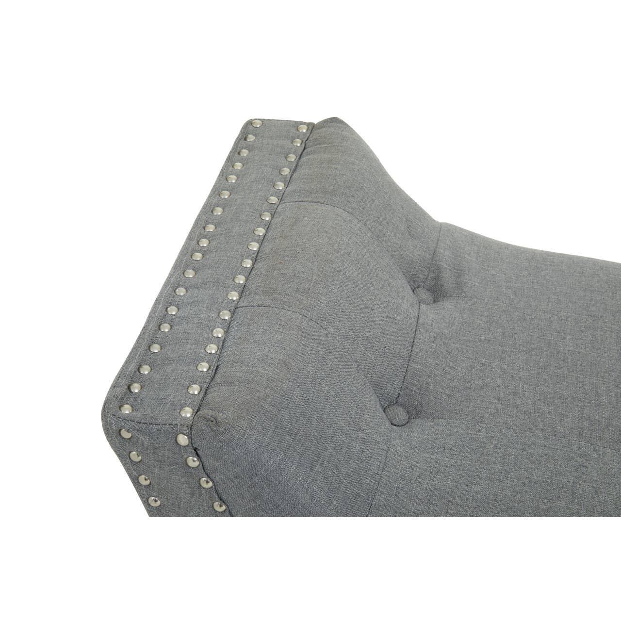 Grey upholstered sofa backrest with button tufting and metal stud detailing