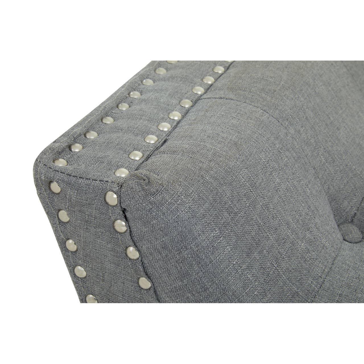 Close-up of grey fabric sofa armrest with metal stud detailing