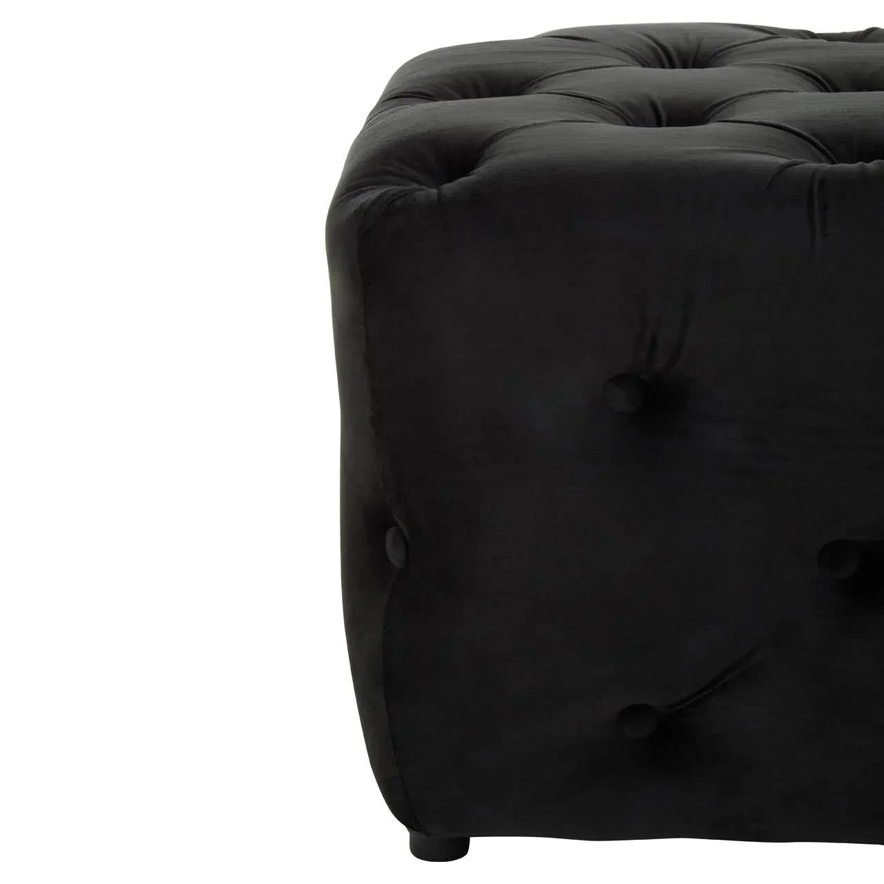 Closeup of black velvet ottoman with deep button tufting and rounded corner