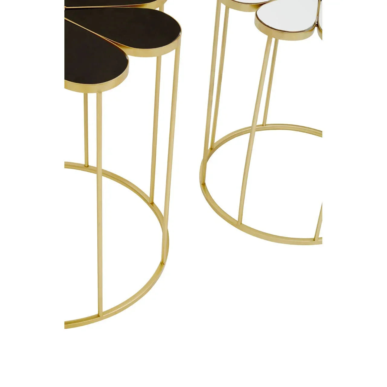 Set of gold metal side tables with petal-shaped black and white tops, close-up view