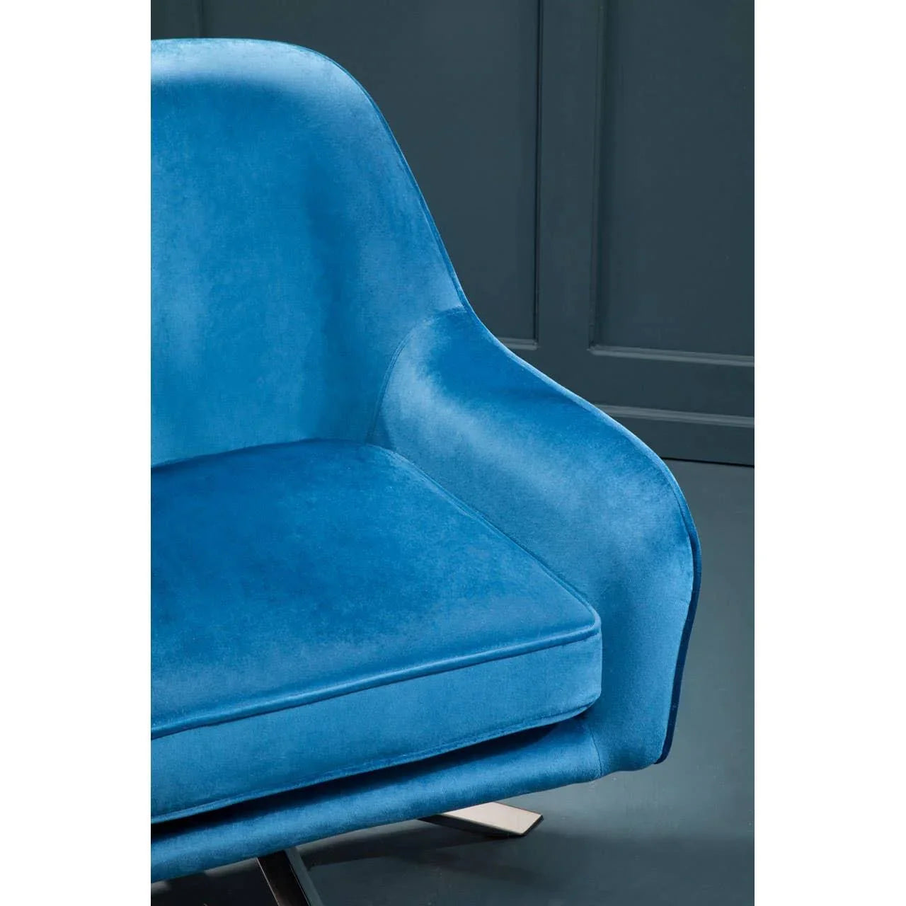Blue velvet accent chair with curved armrest and chrome leg in modern setting