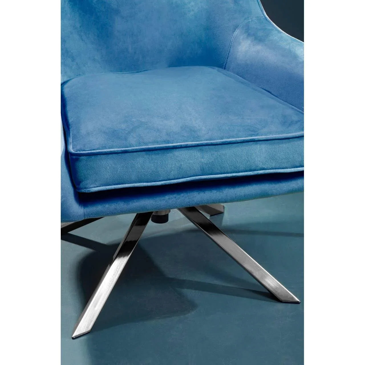 Blue velvet armchair with cushion and chrome swivel legs on blue floor