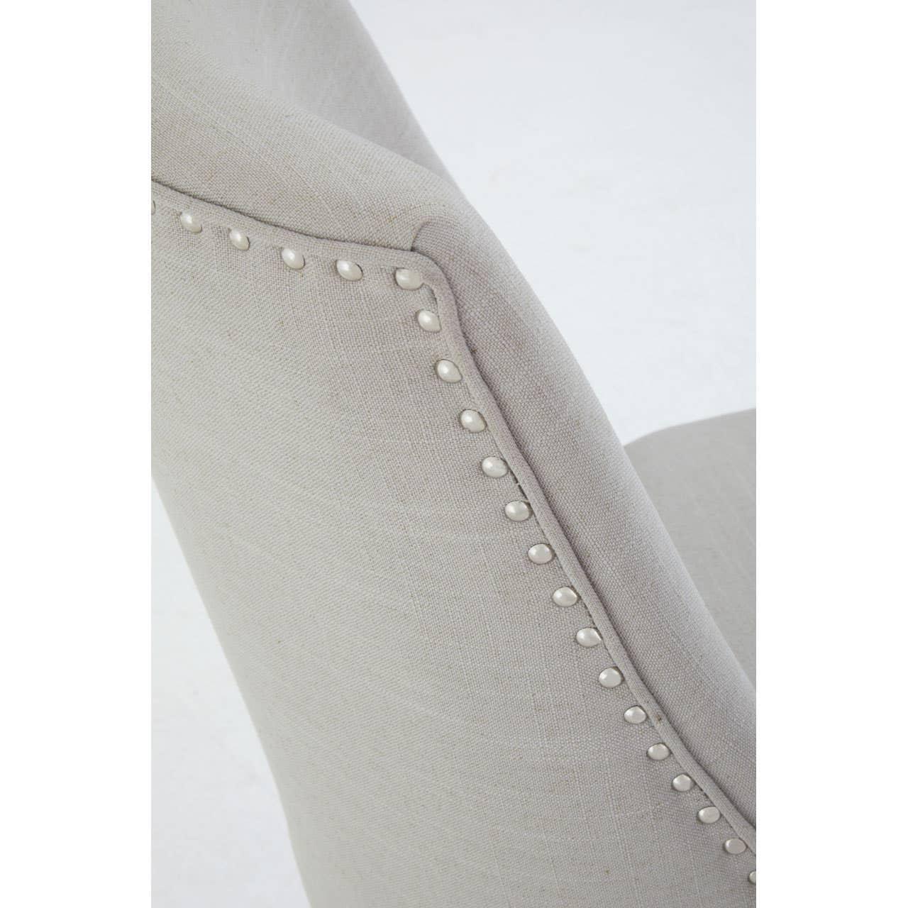 Light grey upholstered dining chair with silver stud detailing on the backrest