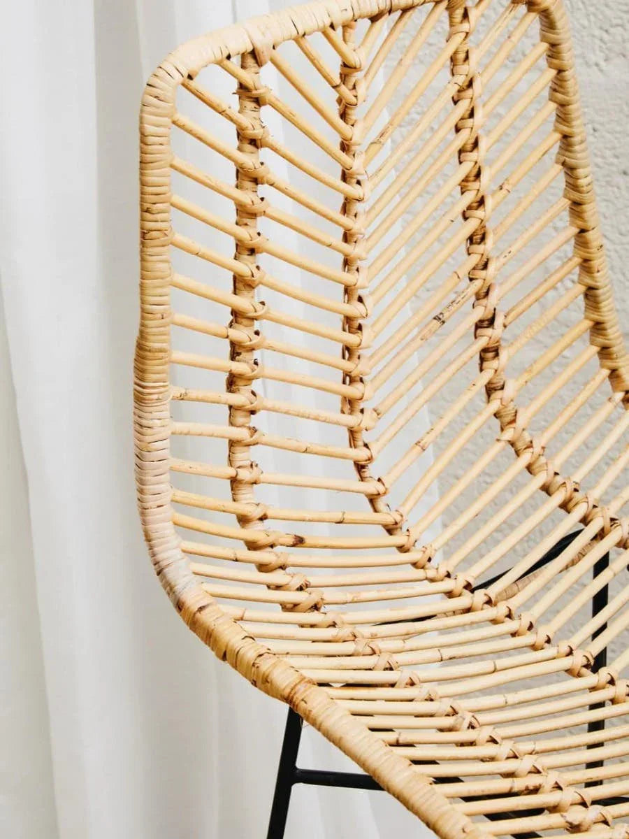 Close-up of rattan dining chair with natural woven seat and black metal legs