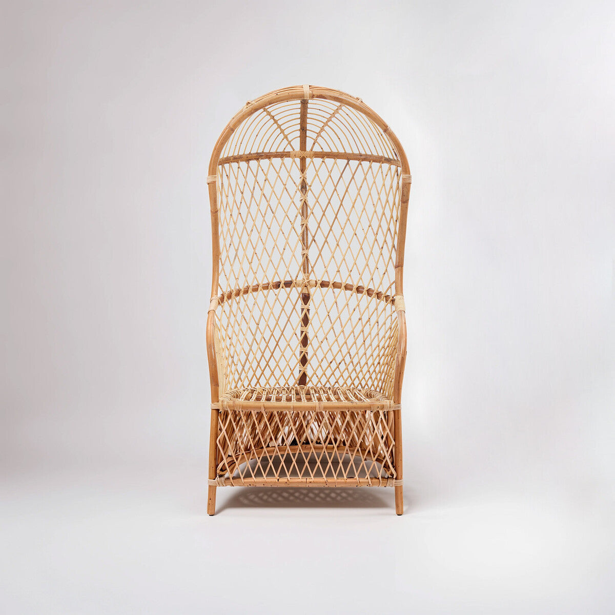 High back chair made of natural rattan with a curved top and woven seat, featuring a light brown finish and an open design that showcases the rattan's texture. The chair stands on a sturdy base, suitable for indoor or outdoor use