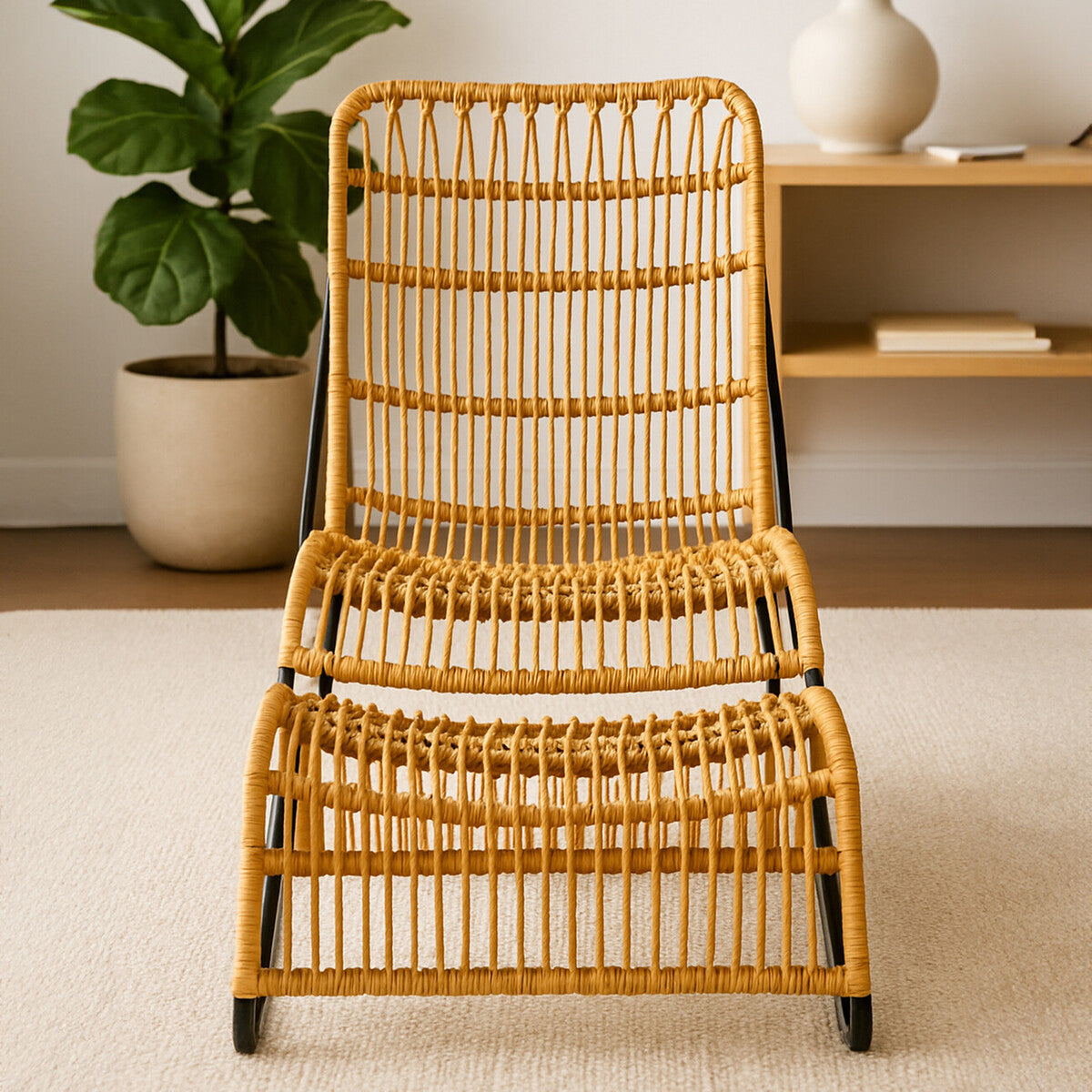 A stylish rattan chair with a curved backrest and a matching footstool, both featuring a natural finish and a woven design. The chair is positioned on a light-colored rug, with a potted plant and a shelf in the background, creating a cozy home environment
