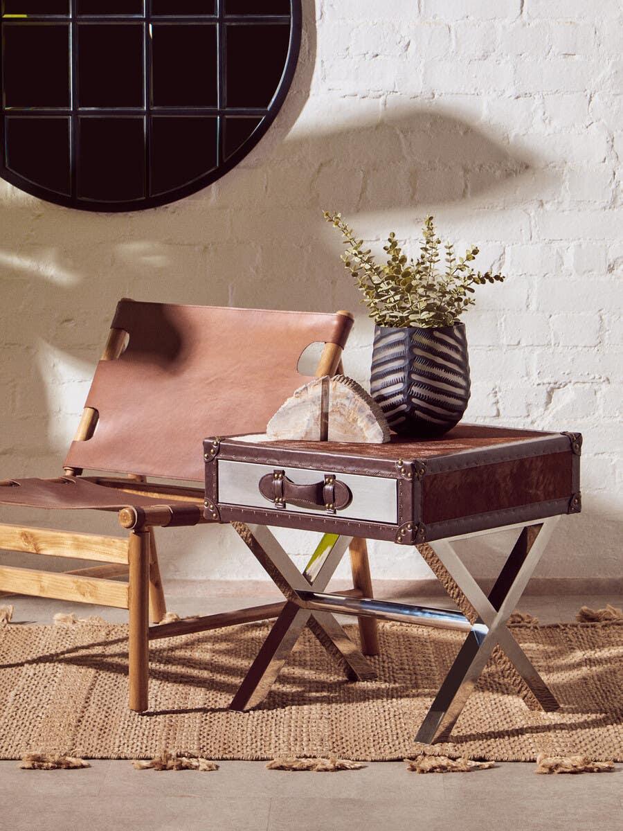 Leather accent chair with wooden frame beside trunk-style side table on jute rug