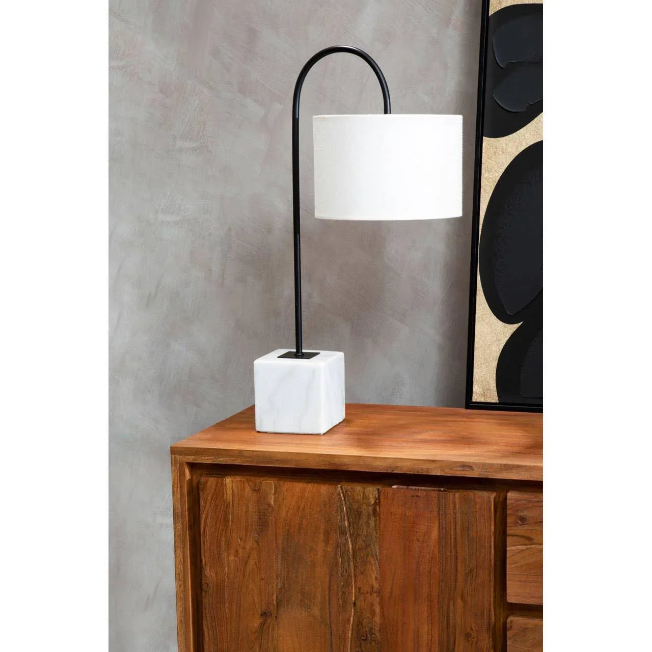 Modern table lamp with white drum shade and marble base on wooden cabinet