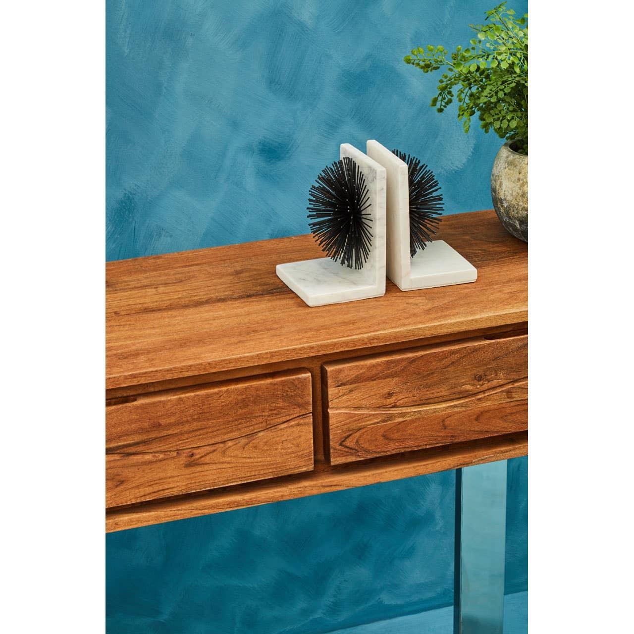 Wood console table with two drawers, marble bookends and potted plant against blue wall