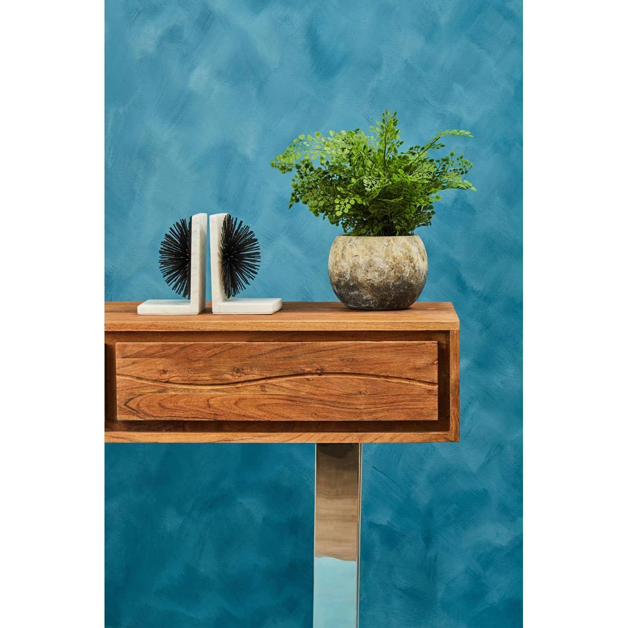 Wooden console table with metal legs, stone plant pot and decorative bookends, blue wall background