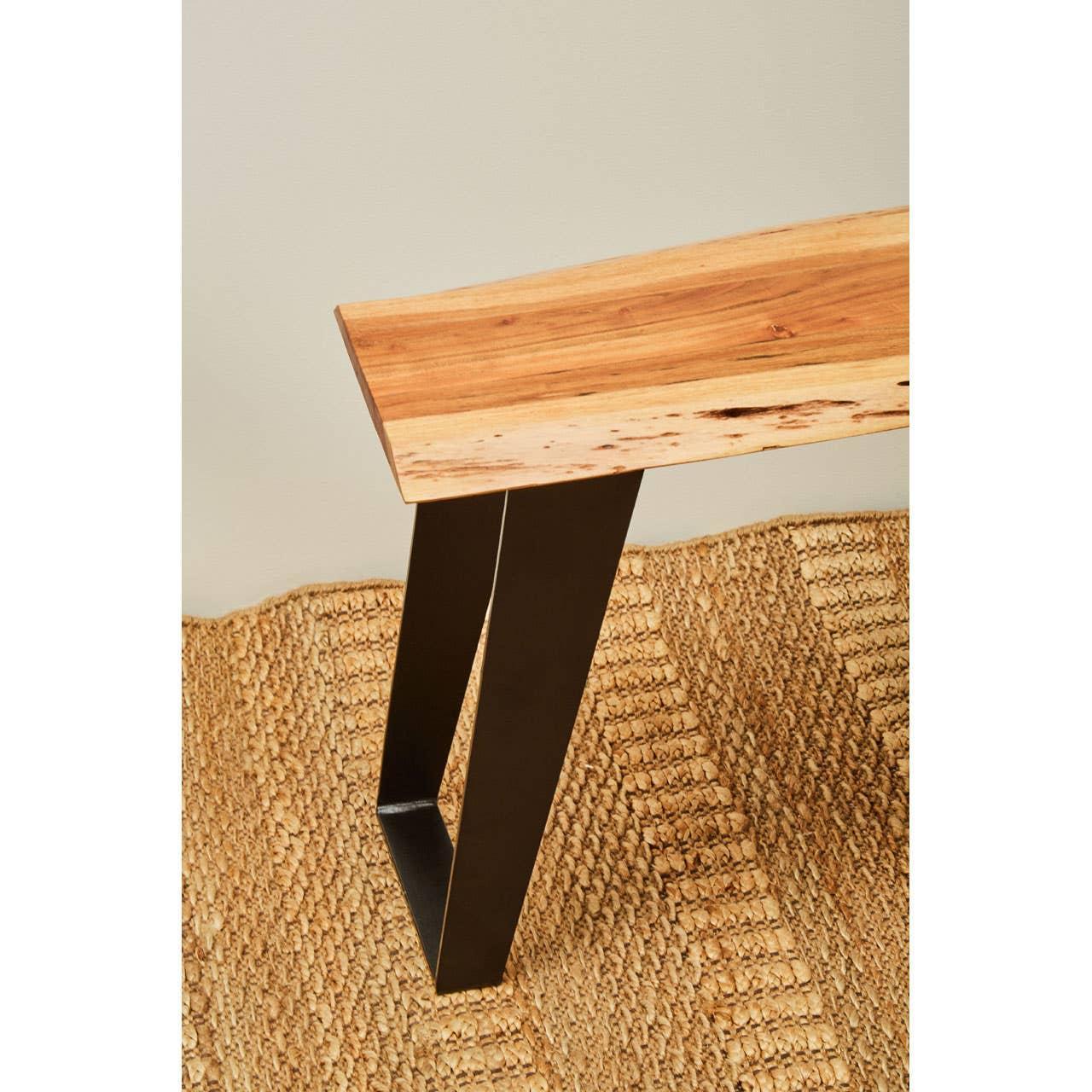 Solid wood dining table with black metal legs on woven jute rug