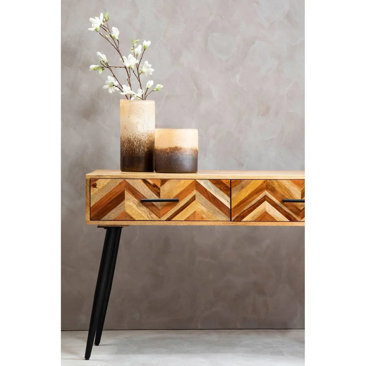 Chevron pattern wooden console table with black legs and ceramic vases with white flowers
