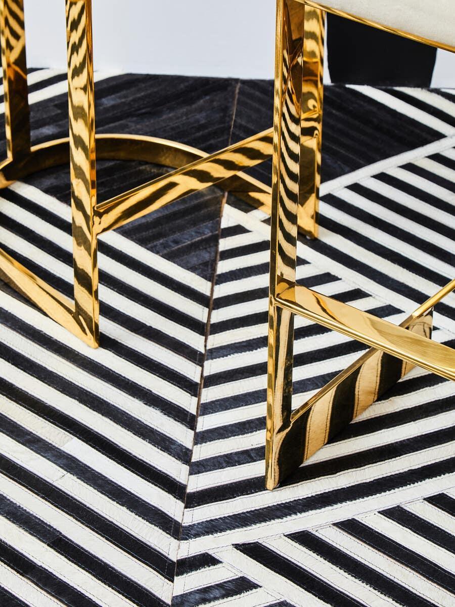 Gold metal dining chair legs on black and white geometric rug
