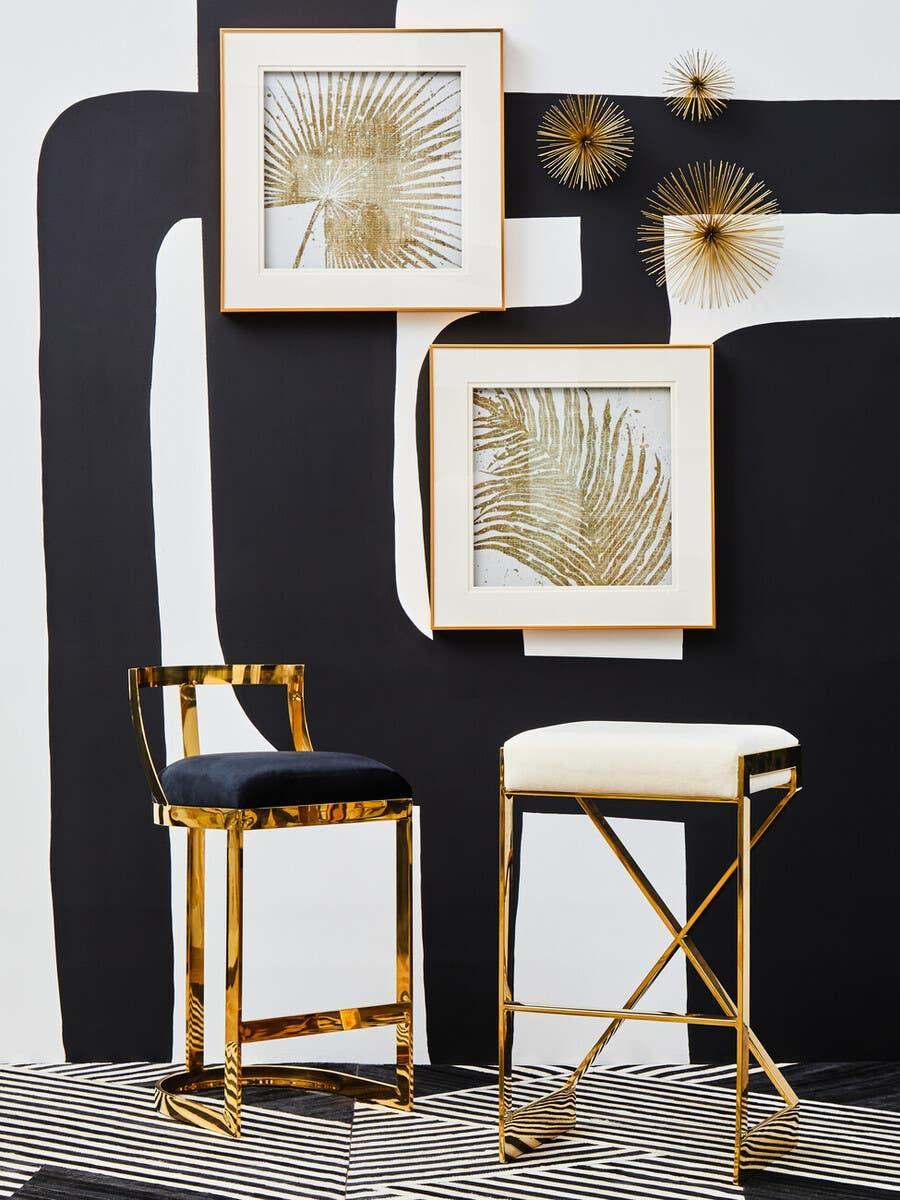Gold bar stools with upholstered seats, black and white wall art, modern interior setting