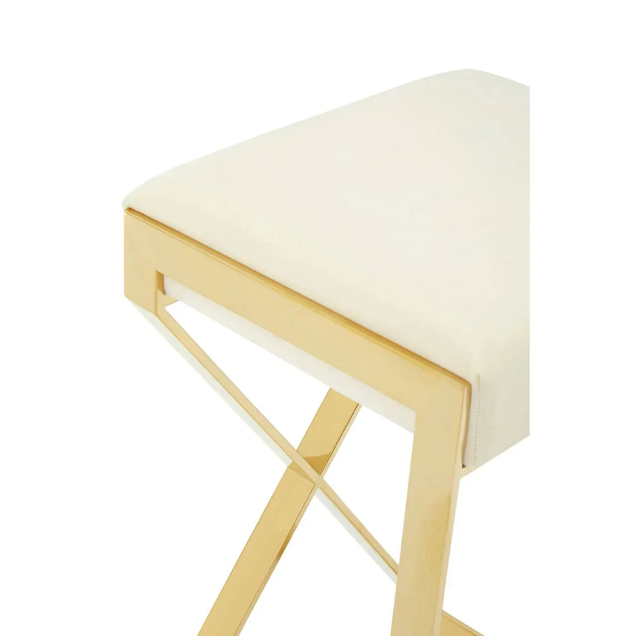 Cream upholstered stool with gold metal frame and crossed leg detail, angled close-up