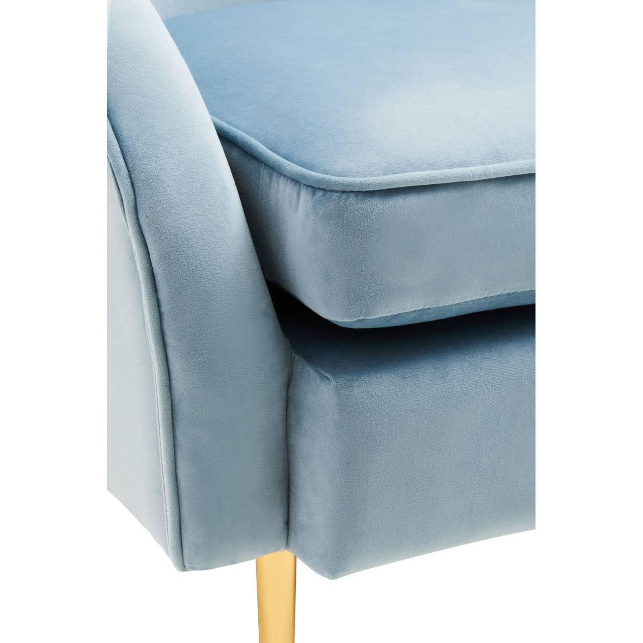 Close-up of blue velvet sofa cushion and armrest with gold metal leg