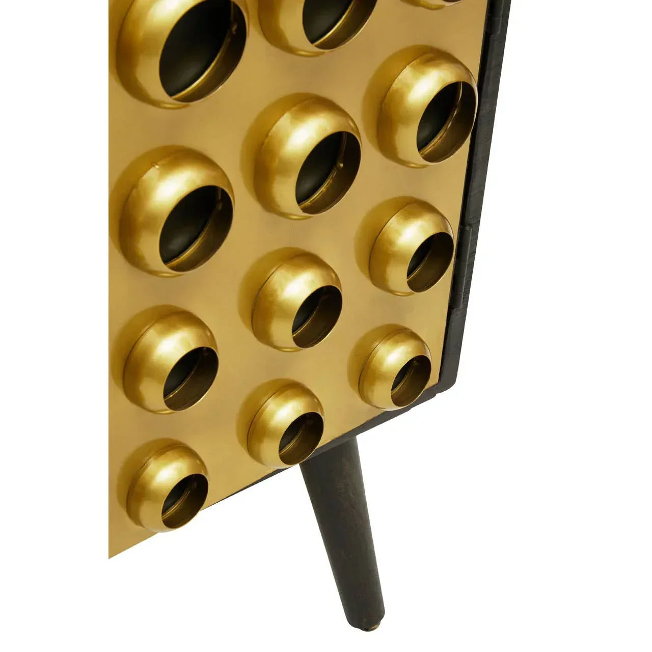 Gold metal cabinet door with circular accents and black angled leg furniture detail