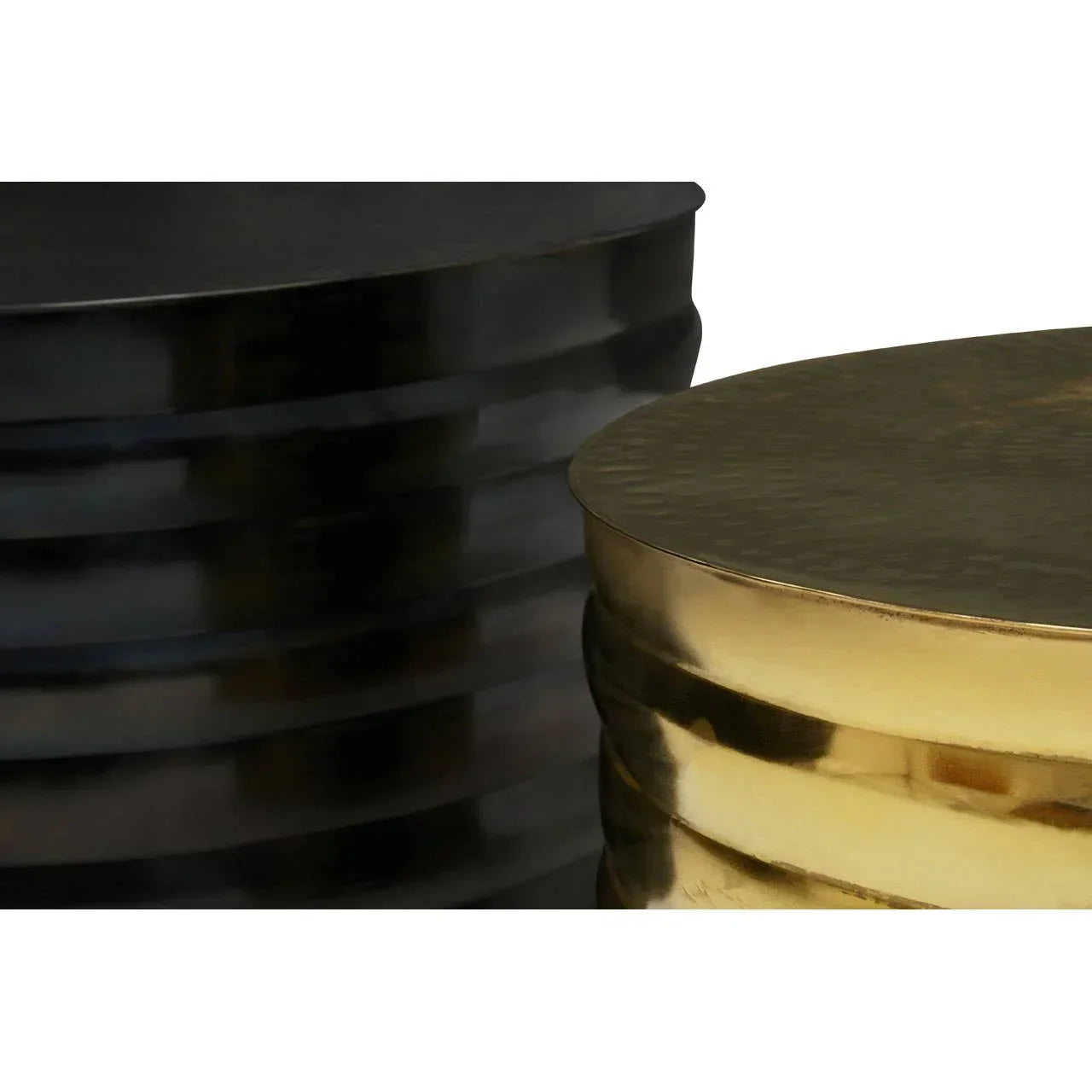 Black and gold metal drum coffee tables with textured surfaces, close angle view