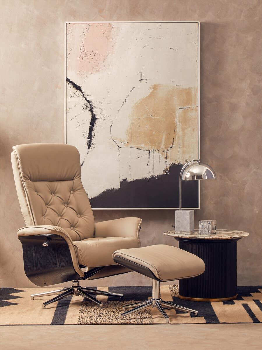Beige recliner chair with footstool, marble side table and abstract wall art in modern living room