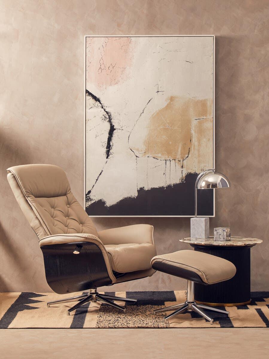 Beige reclining armchair with matching footstool beside a round marble side table in living room