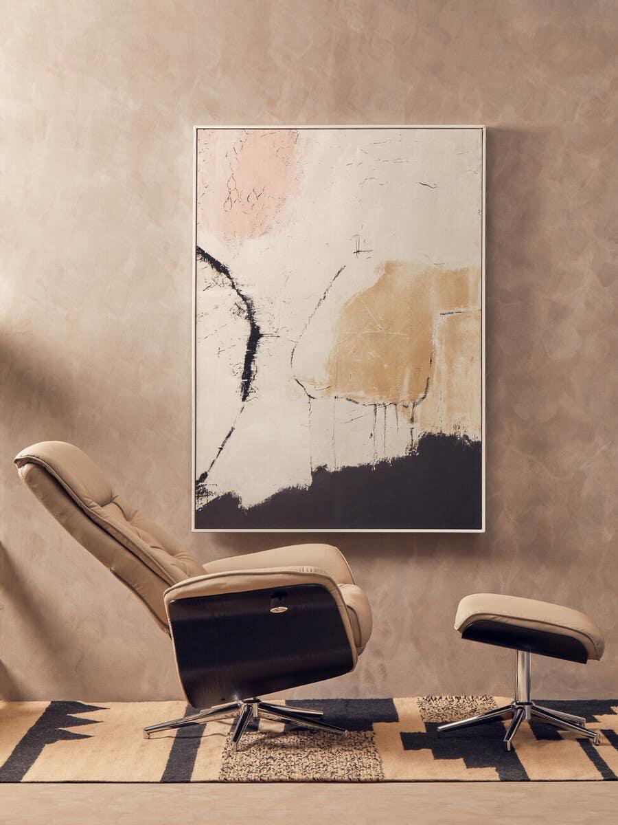Beige leather recliner chair with matching footstool on patterned rug against abstract wall art