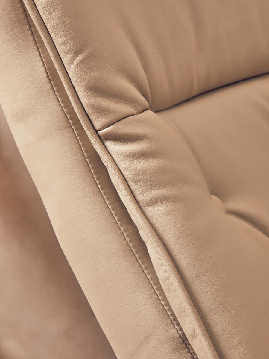 Close up of beige leather sofa with soft tufted upholstery and detailed stitching