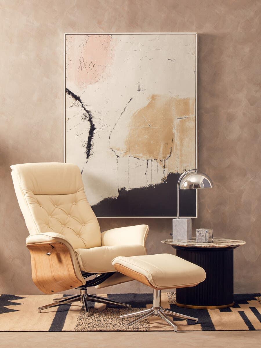 Cream leather recliner chair with matching footstool and round side table in modern lounge