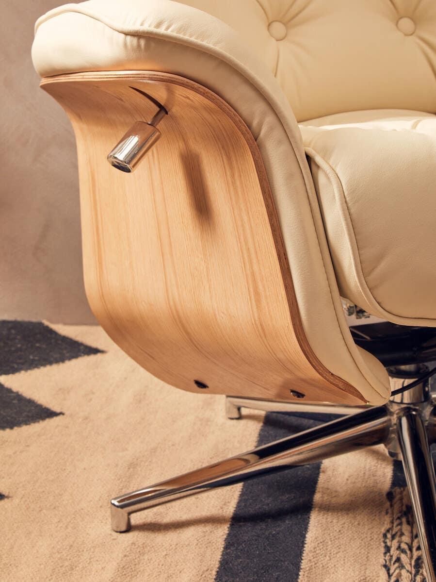 Beige leather armchair with wooden back and chrome swivel base on patterned rug