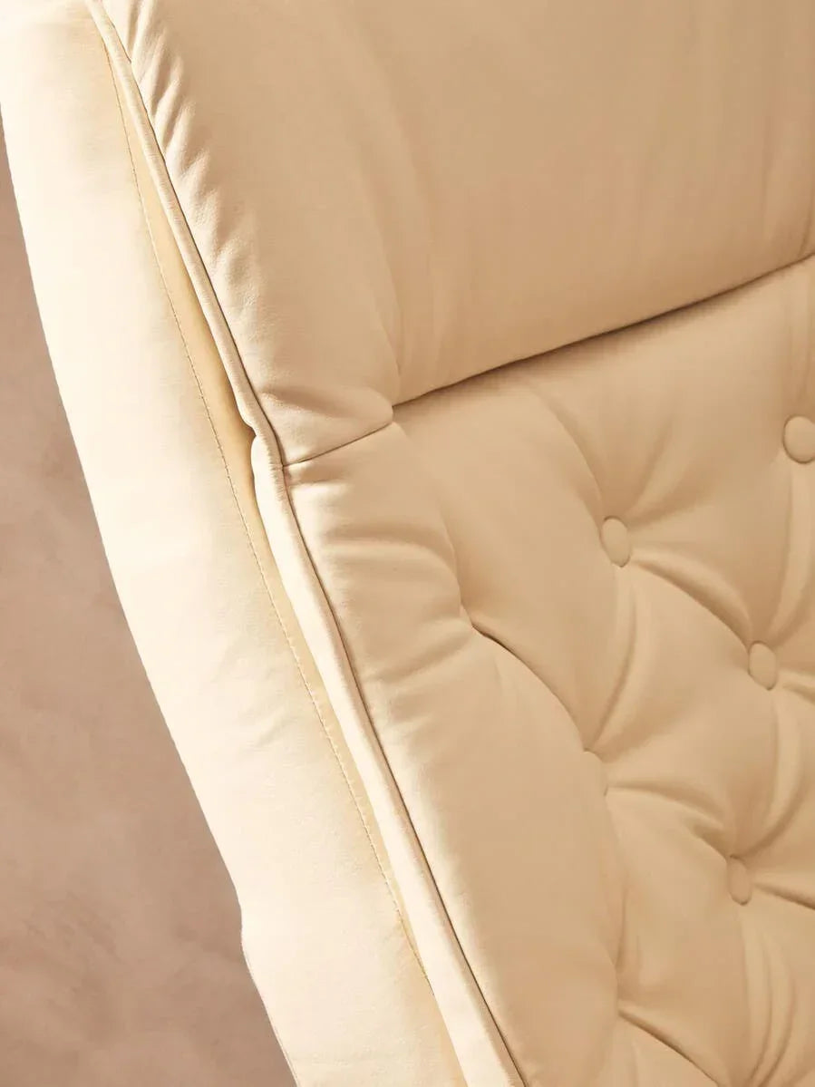 Close-up of cream fabric armchair with deep button tufting and plush backrest cushion