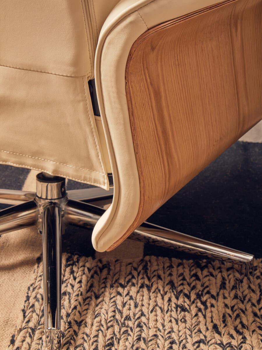 Beige leather office chair with wood panel and chrome base on woven rug