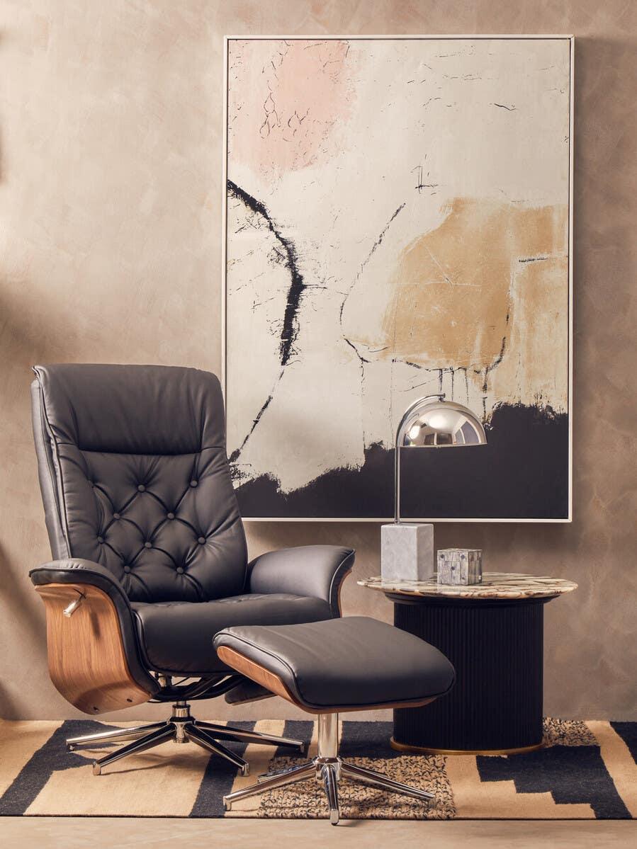 Black leather swivel armchair and footstool with wood frame beside round marble side table