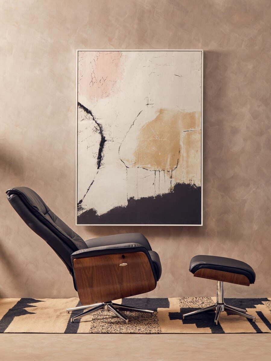 Black leather recliner chair and footstool with wood sides on patterned rug