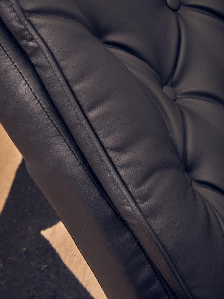 Close-up of black leather sofa cushion with detailed tufting and stitching
