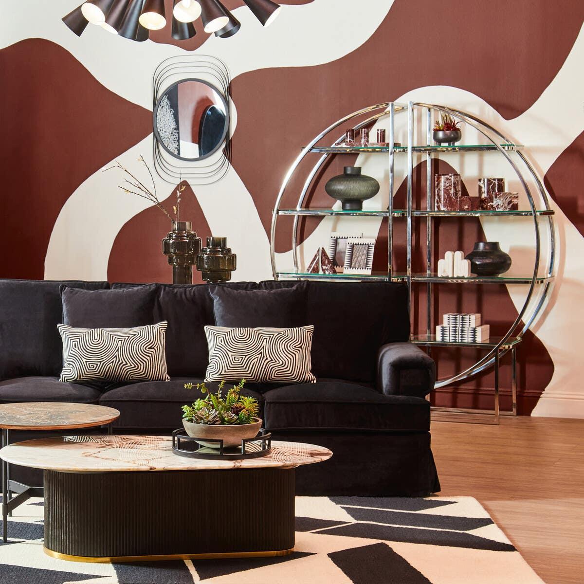 Velvet black sofa with patterned cushions and marble coffee table in modern living room