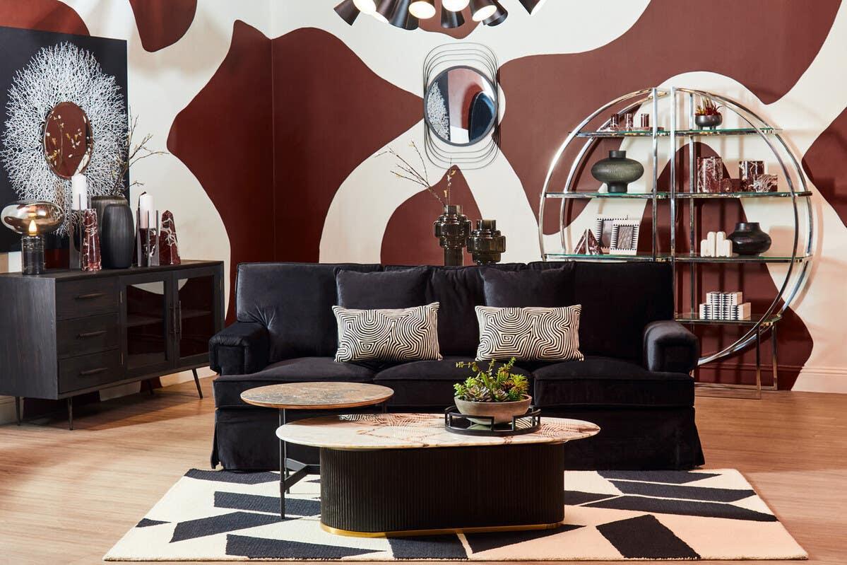 Velvet black sofa with patterned cushions, modern coffee tables and geometric accent rug