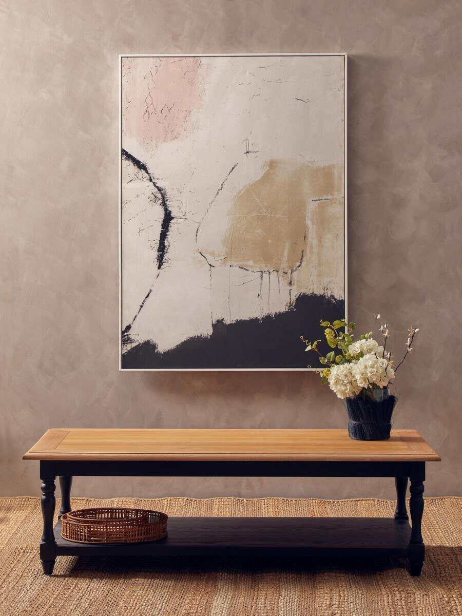 Wooden coffee table with black legs, lower shelf, basket, and floral arrangement in living room