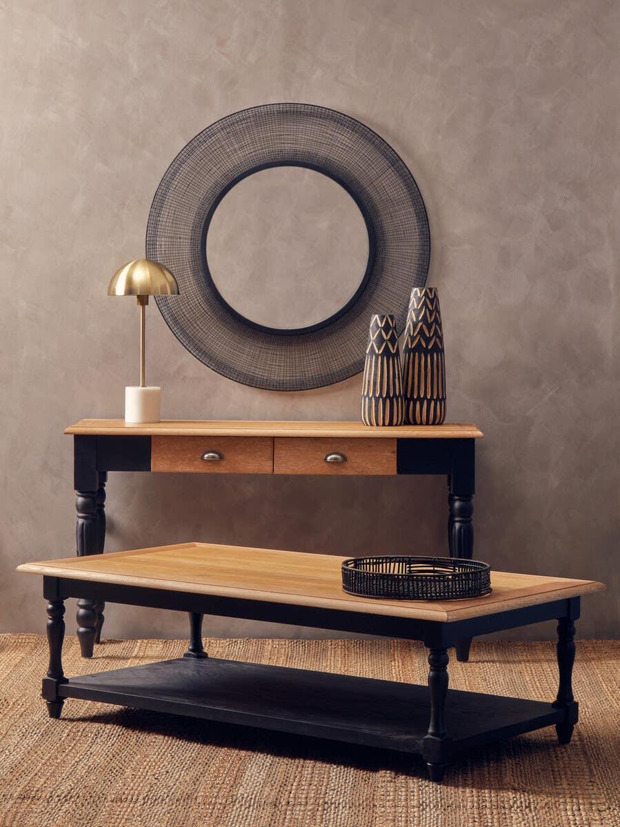 Wood and black console table with drawers, matching coffee table, round mirror, and decor vases