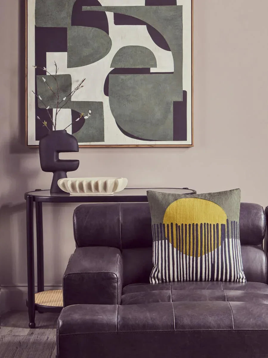 Modern black leather sofa with yellow geometric cushion and abstract wall art in living room