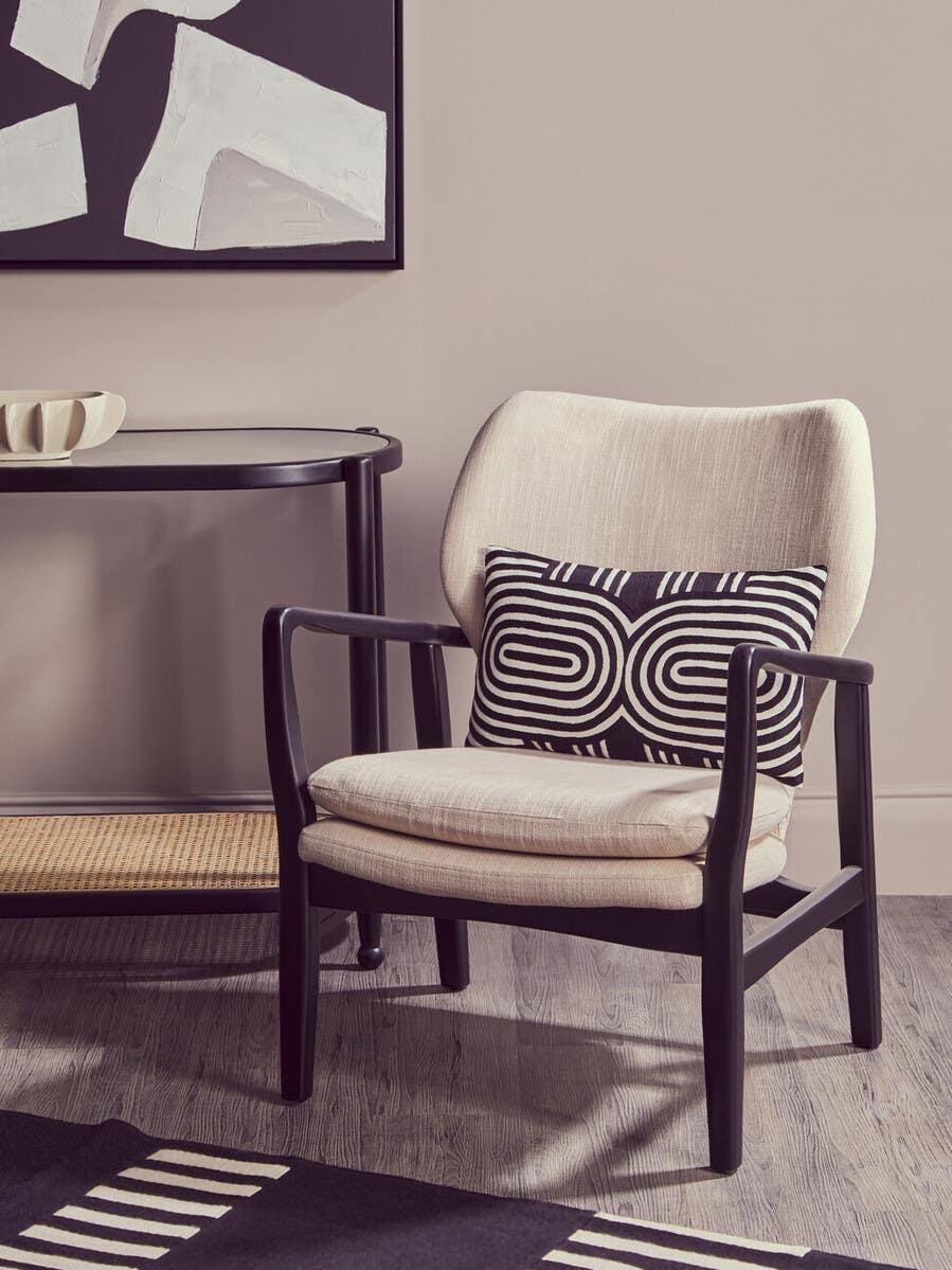 Beige accent chair with black wooden frame and patterned cushion in modern living room