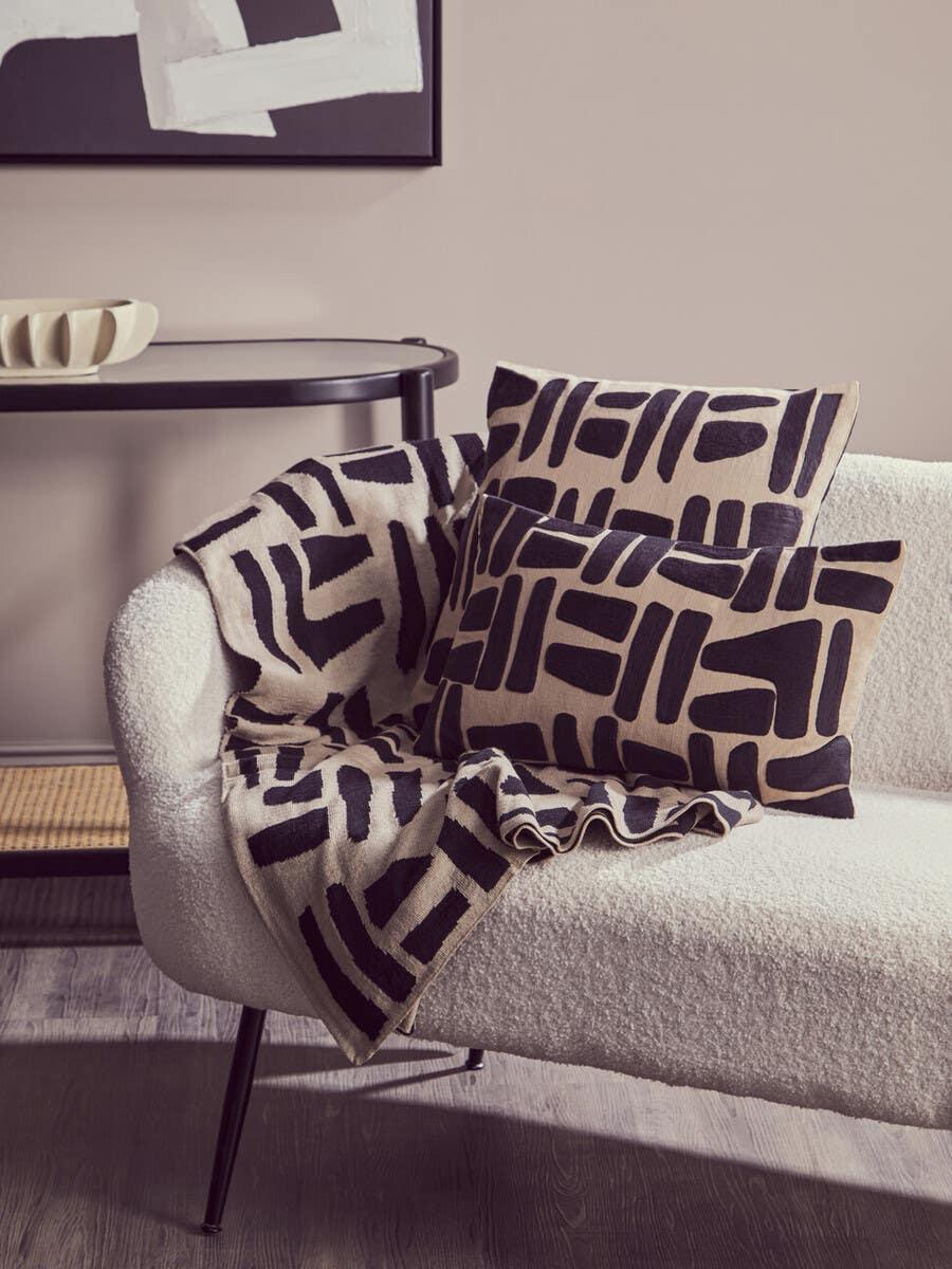 Cream sofa with black geometric cushions and throw in modern living room setting