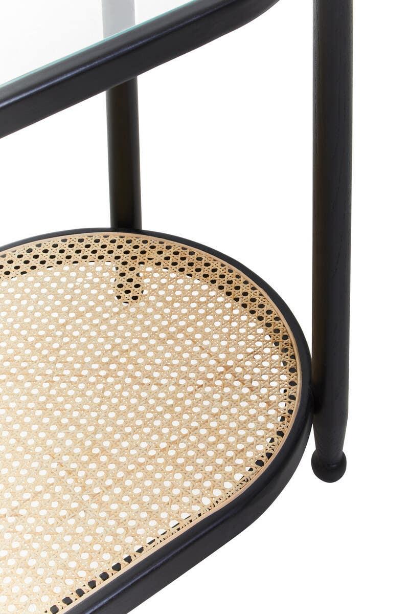 Round rattan shelf with black wooden frame and glass top, detail view of furniture design
