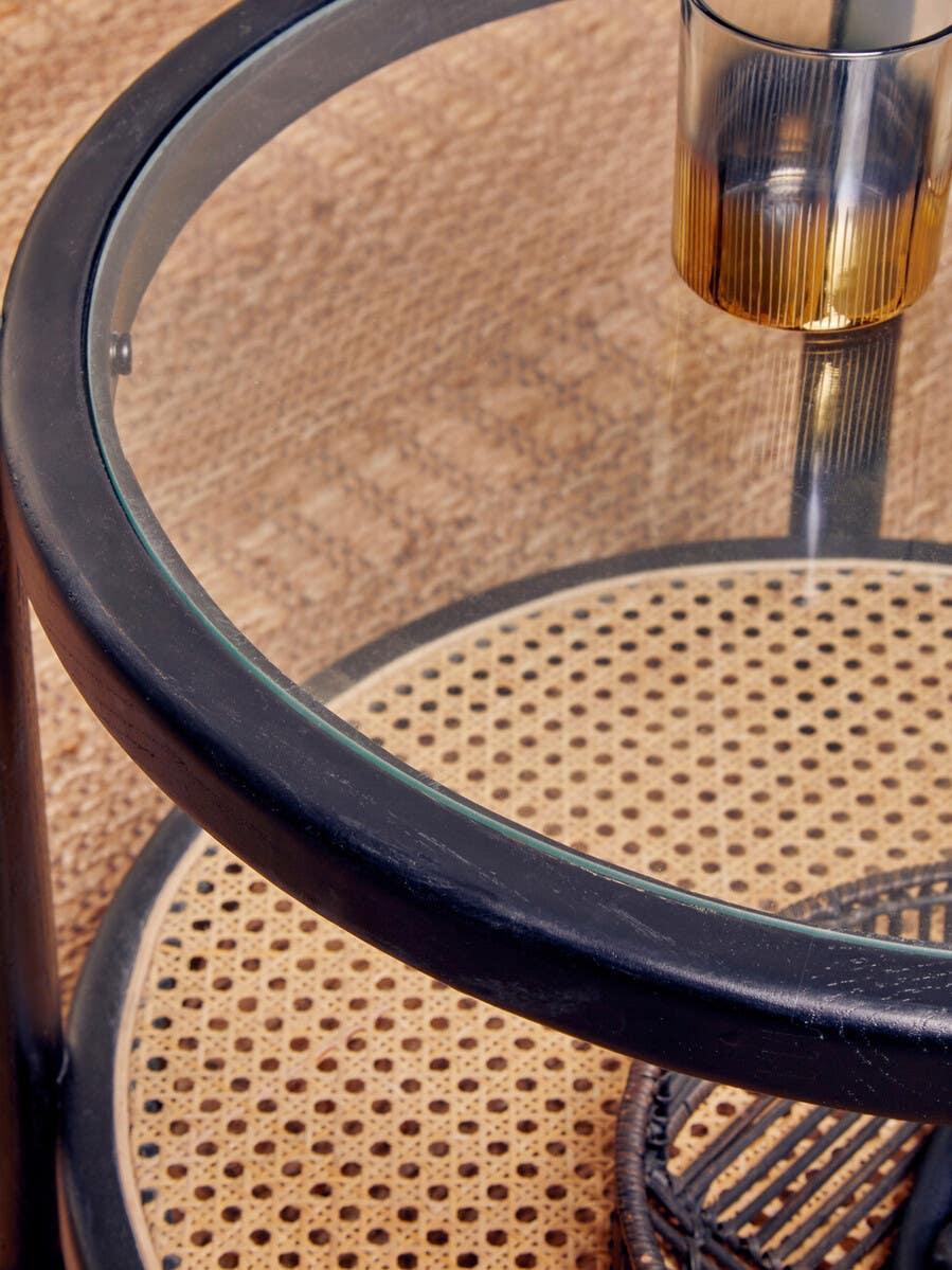 Round glass coffee table with black frame and cane shelf, amber glass on top