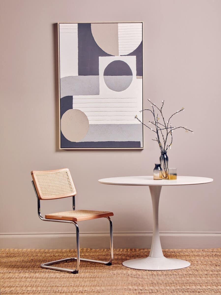 Rattan dining chair with chrome frame beside round white dining table in modern room