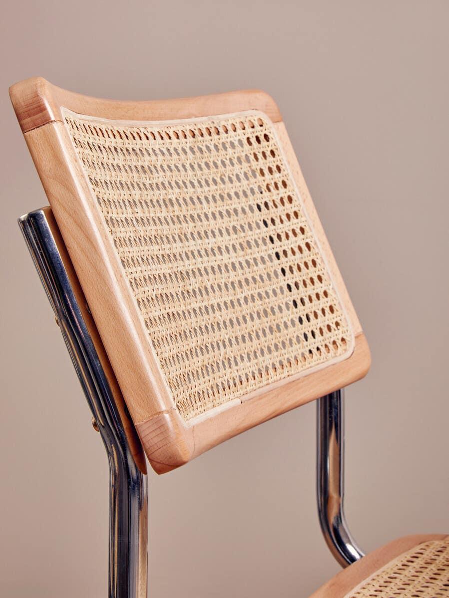 Closeup of a rattan dining chair with wooden frame and chrome legs