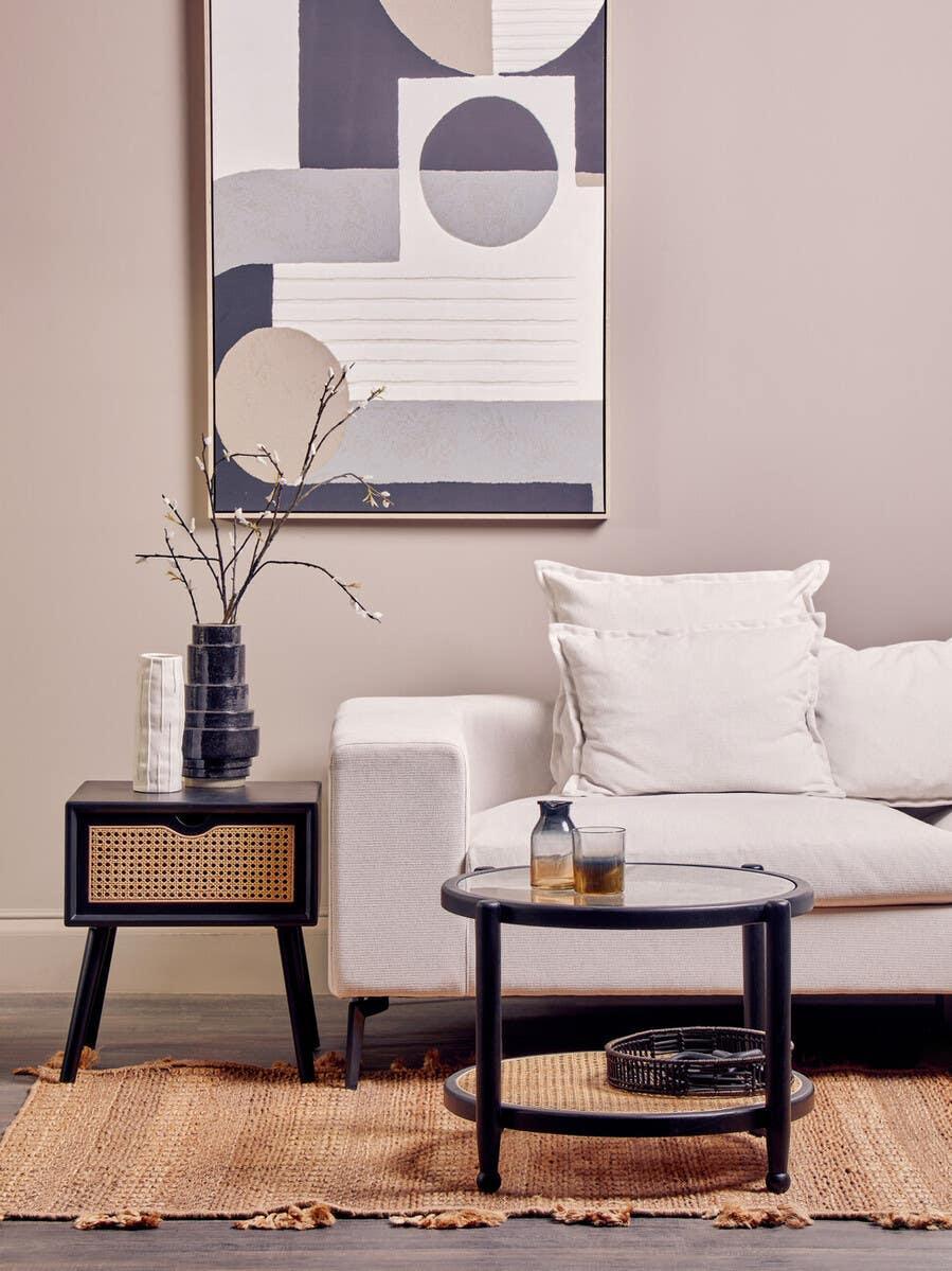 Modern white sofa with black coffee table and rattan side table in neutral living room