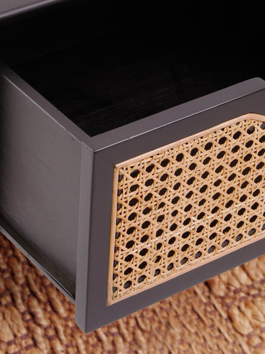 Close-up of wooden drawer with rattan panel and black finish on woven rug
